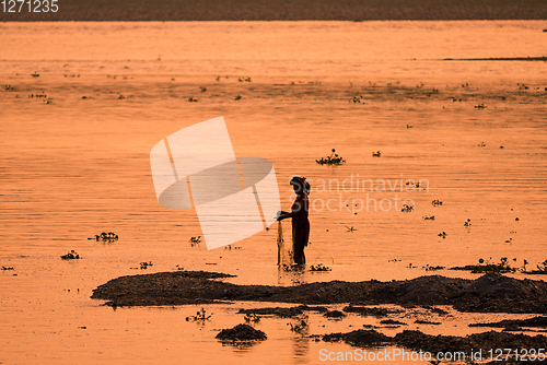 Image of Asian Woman fishing in the river, silhouette at sunset