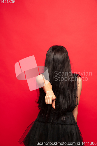 Image of Young woman in hat and dress as a witch on red background