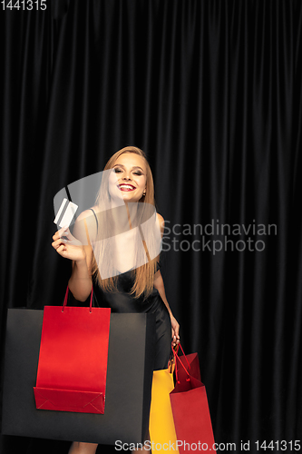 Image of Young woman in dress shopping on black background