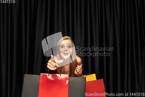 Image of Young woman in dress shopping on black background