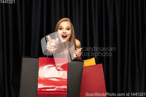 Image of Young woman in dress shopping on black background