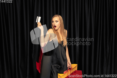 Image of Young woman in dress shopping on black background