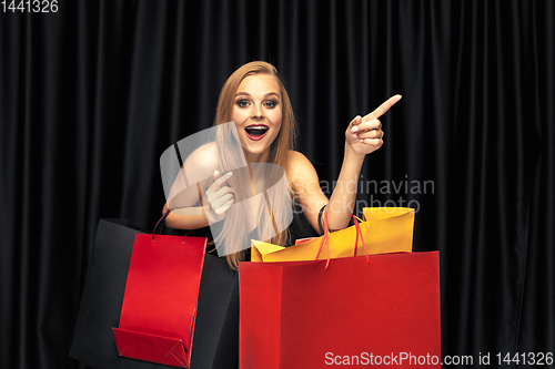 Image of Young woman in dress shopping on black background