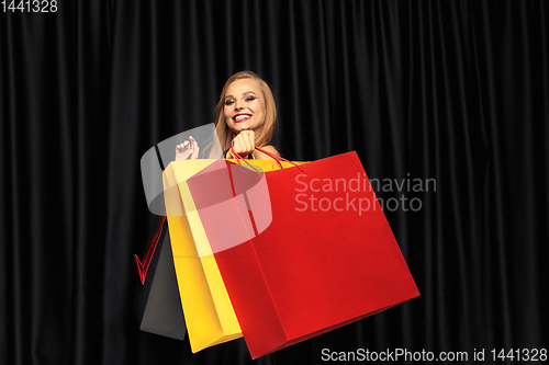 Image of Young woman in dress shopping on black background