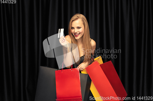 Image of Young woman in dress shopping on black background