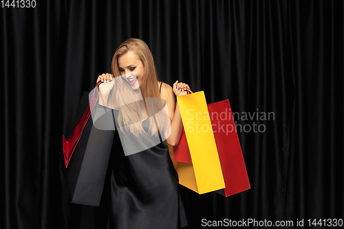 Image of Young woman in dress shopping on black background
