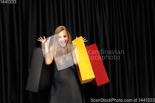 Image of Young woman in dress shopping on black background