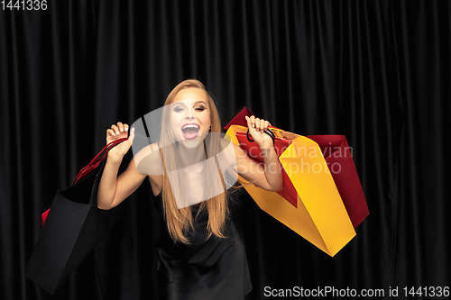 Image of Young woman in dress shopping on black background