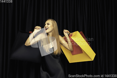 Image of Young woman in dress shopping on black background