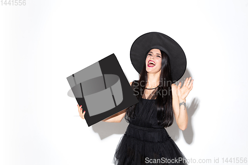 Image of Young woman in hat and dress as a witch on white background