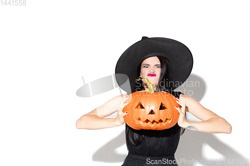 Image of Young woman in hat and dress as a witch on white background