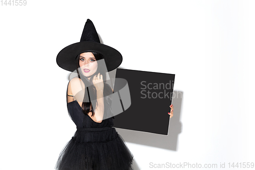 Image of Young woman in hat and dress as a witch on white background