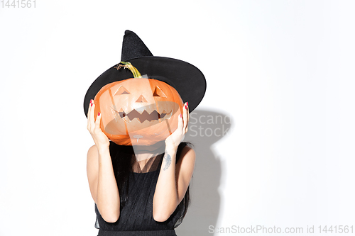 Image of Young woman in hat and dress as a witch on white background