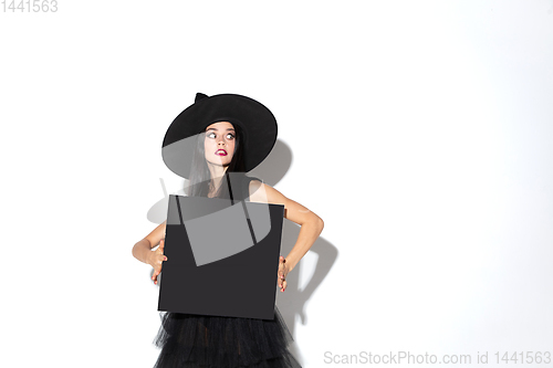 Image of Young woman in hat and dress as a witch on white background