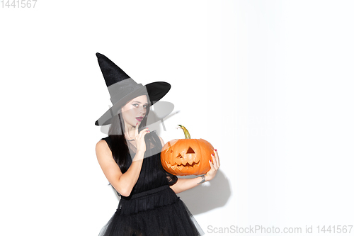 Image of Young woman in hat and dress as a witch on white background