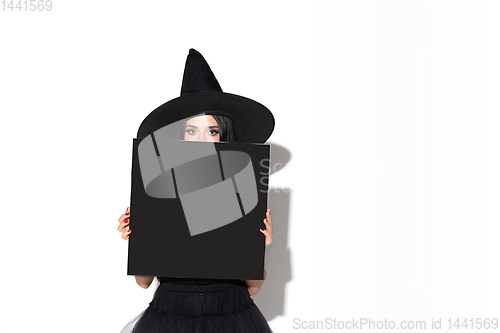 Image of Young woman in hat and dress as a witch on white background