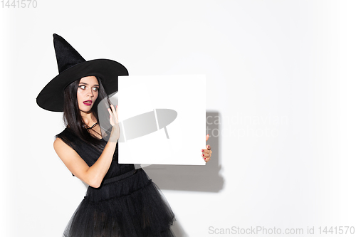 Image of Young woman in hat and dress as a witch on white background