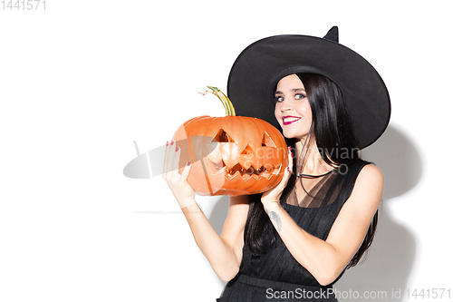 Image of Young woman in hat and dress as a witch on white background