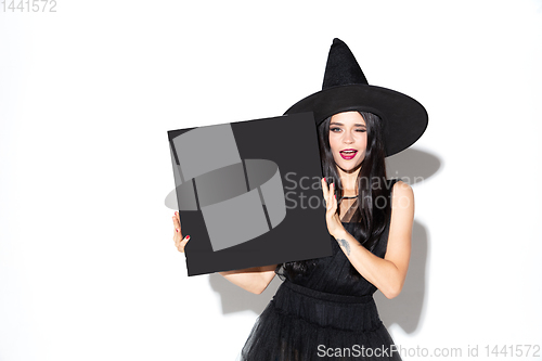 Image of Young woman in hat and dress as a witch on white background