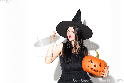 Image of Young woman in hat and dress as a witch on white background