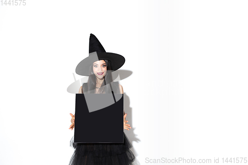 Image of Young woman in hat and dress as a witch on white background