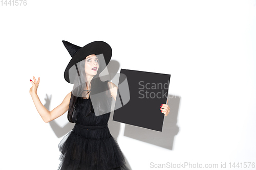 Image of Young woman in hat and dress as a witch on white background