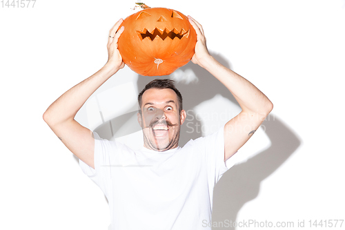 Image of Young man holding pumpking on white background