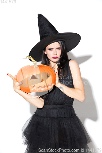 Image of Young woman in hat and dress as a witch on white background