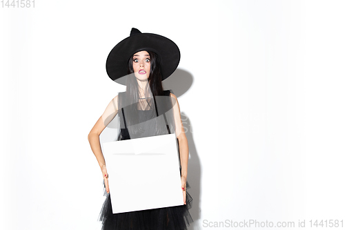 Image of Young woman in hat and dress as a witch on white background