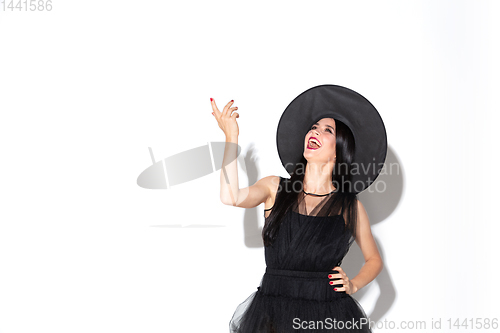 Image of Young woman in hat and dress as a witch on white background