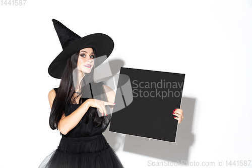 Image of Young woman in hat and dress as a witch on white background