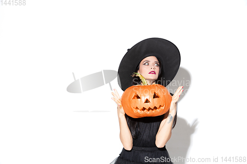 Image of Young woman in hat and dress as a witch on white background