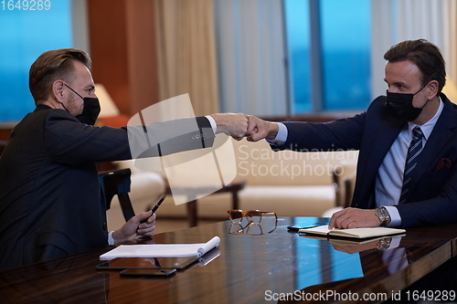 Image of business people wearing face mask on meeting and handshake