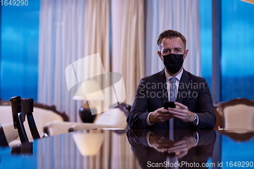 Image of business man using smart phone at luxury office wearing face mask