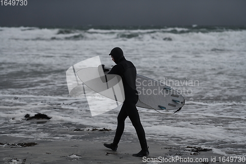 Image of Arctic surfer going by beach after surfing