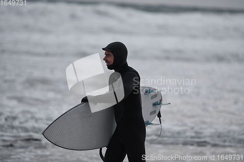 Image of Arctic surfer going by beach after surfing