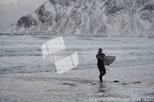 Image of Arctic surfer going by beach after surfing