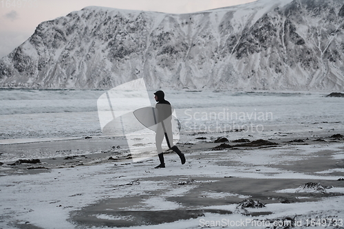 Image of Arctic surfer going by beach after surfing