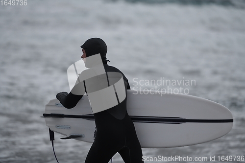 Image of Arctic surfer going by beach after surfing