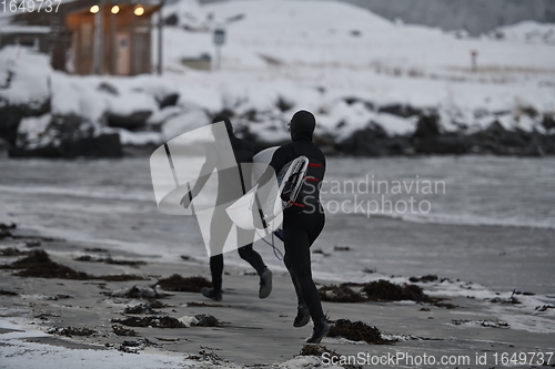 Image of Arctic surfers running on beach after surfing