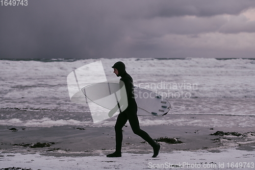 Image of Arctic surfer going by beach after surfing