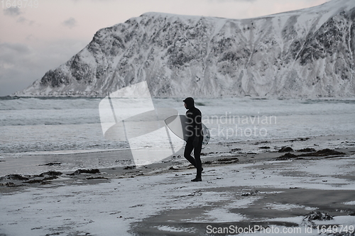 Image of Arctic surfer going by beach after surfing