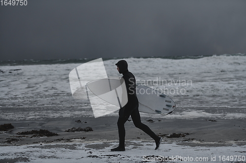 Image of Arctic surfer going by beach after surfing