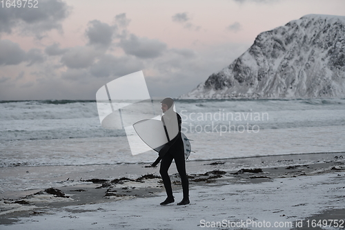 Image of Arctic surfer going by beach after surfing