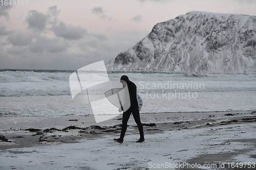 Image of Arctic surfer going by beach after surfing