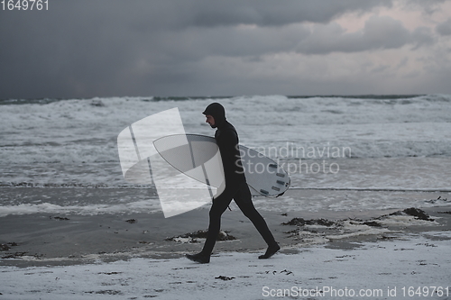 Image of Arctic surfer going by beach after surfing