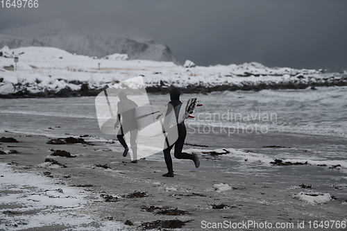 Image of Arctic surfers running on beach after surfing