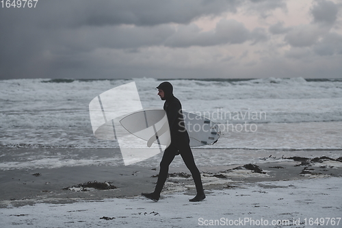 Image of Arctic surfer going by beach after surfing