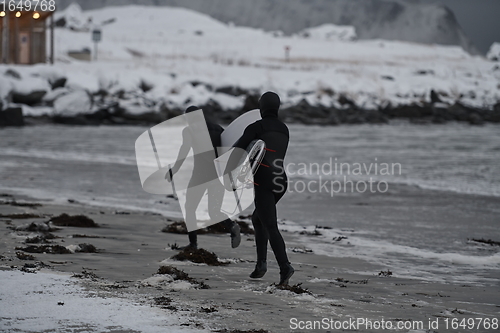 Image of Arctic surfers running on beach after surfing