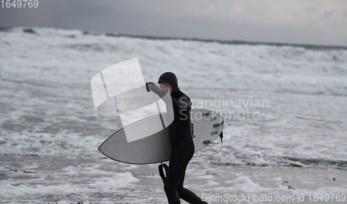 Image of Arctic surfer going by beach after surfing